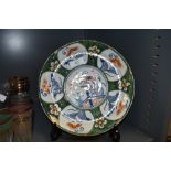 An antique Dutch delft plate with unusual green ground under typical blue and red colour ways and