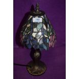 A modern Tiffany style lamp having brass stem and purple,pink and blue green hues to shade.