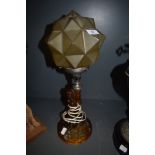 An art deco amber glass desk lamp having figure of naked maiden to base holding star like shade.