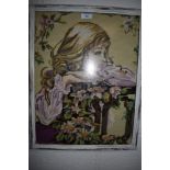 A framed needlepoint depicting young woman and floral scene.