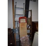 A vintage ironing board and set of aluminium ladders