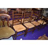 A set of six plus carver dining chairs having rush seats with traditional ladder back design