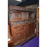 A period oak court cupboard having extensive carved detail to panels depicting wyvern or dragons