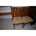 A pair of early 20th Century oak dining chairs having shaped slat backs and stuffed seats, real nice