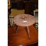 An Eastern style carved stool or occasional table on tripod legs