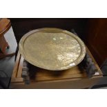 An Eastern carved brass top folding table, top a bit bashed and some of inlay missing, diameter