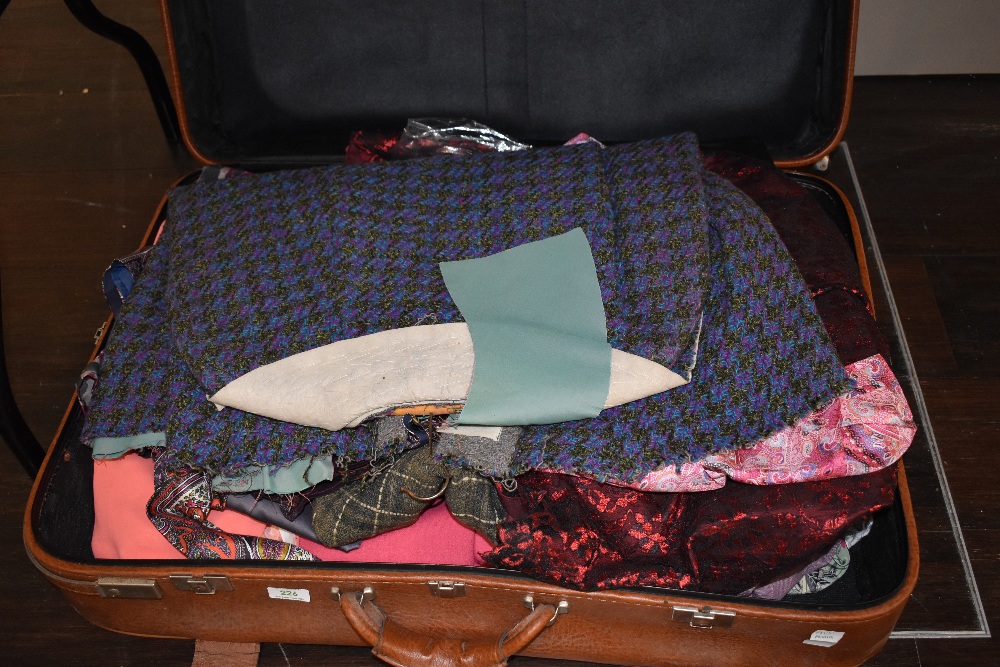 A suitcase containing vintage and retro clothing alongside and unfinished Welsh wool style cape.