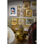 An antique brass desk top oil lamp with glass chimney.