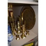 Eleven brass candlesticks and a embossed decorative wall plaque.