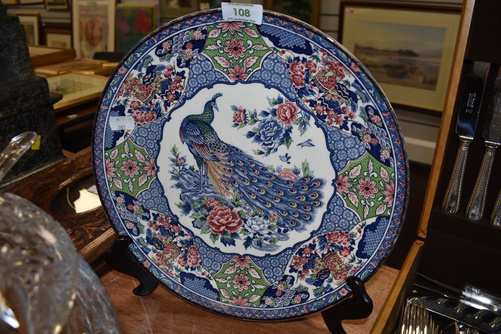 A mid century Japanese export display plate having transfer pattern depicting peacock and peonies.