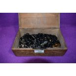 A carved treen box containing a selection of costume jewellery including two mourning jewellery muff