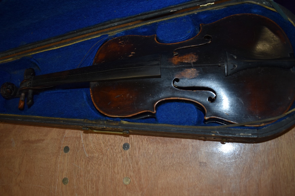 A distressed dark stained 19th Century violin having lion mask scroll, on piece back and traditional