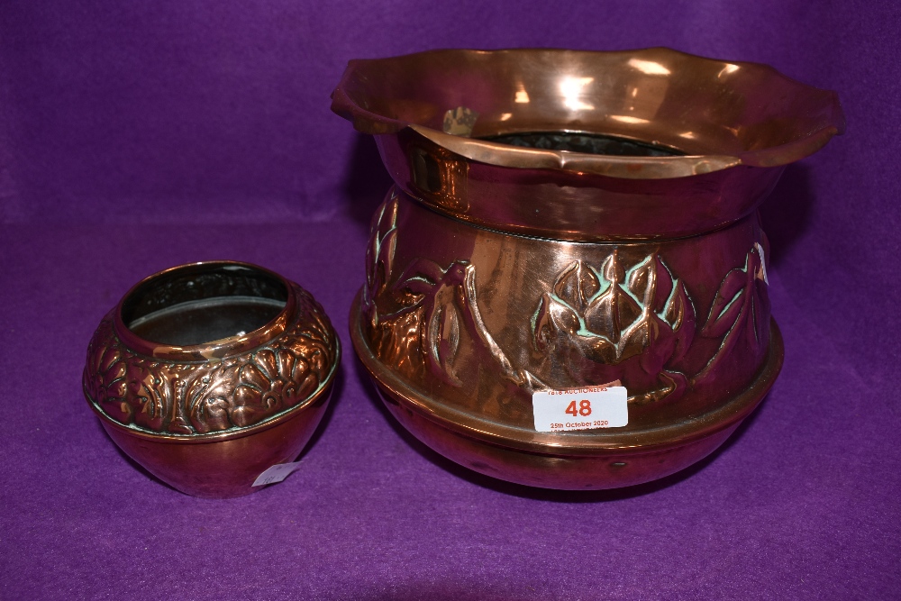 An arts and crafts copper planter with embossed design and smaller pot with similar design, both are