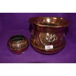 An arts and crafts copper planter with embossed design and smaller pot with similar design, both are