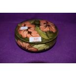 A vintage Moorcroft lidded bowl having orange hibiscus pattern on green ground.