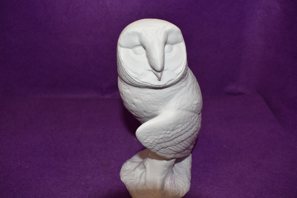 A figure of an owl by Beswick in a bisque ceramic and stamped to base