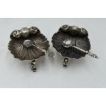 A pair of Victorian silver salts in the form of scallop shells on trefoil mythical fish feet,