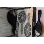 A cased silver four piece dressing table set having repousse mask, bird and scroll decoration,