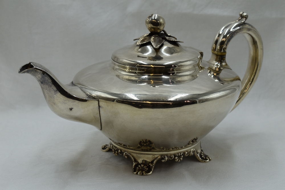 A Georgian silver teapot of plain compressed circular form having bracket feet, scroll handle and