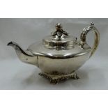 A Georgian silver teapot of plain compressed circular form having bracket feet, scroll handle and