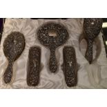 A cased five piece silver dressing table set having embossed mask, bird and scroll decoration,