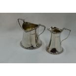 An Edwardian silver cream jug and sugar bowl of plain waisted form having moulded decoration to