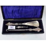 A cased Edwardian silver trio set of button hooks and shoe horn having moulded silver handles,