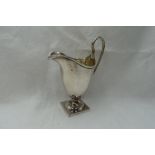 An Edwardian silver cream jug of plain helmet form having reided loop handle and square platform