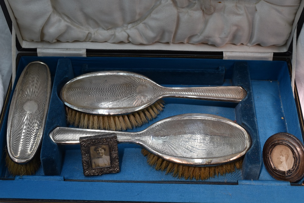 A cased part set of silver dressing table brushes having having engine turned moon shine decoration,