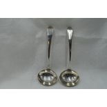 A pair of Georgian silver ladles of plain form bearing sun burst crest to terminals, London 1802,