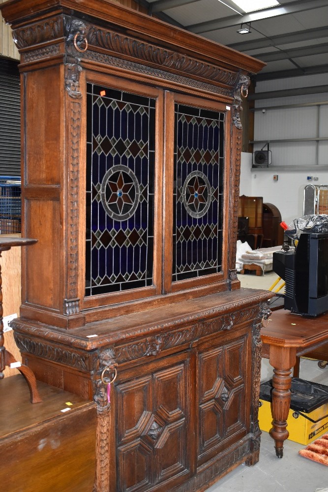 A Victorian oak bookcase having cupboard base, with lion mask carvings, upper section with