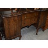 An early to mid 20th Century mahogany or dark walnut sideboard having shaped top