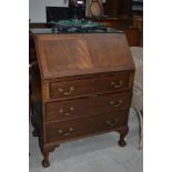 An early 20th Century mahogany bureau having flap top, three long drawers on ball and claw feet,