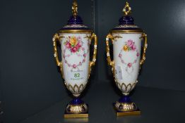 .A pair of two hand decorated Royal Worcester urns hand painted by E.Phillips