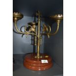 An arts and crafts brass candlestick holder having three swinging arms with ivy decoration and cross