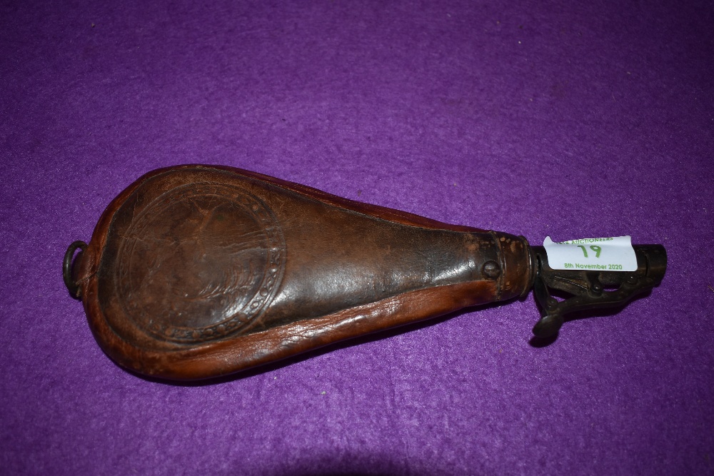 A Victorian leather shot dispenser having hunting scene with gun dog and bird embossed detail.