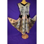 A vintage 1950s gold dress with flocked pattern and black velvet detailing to neckline and skirt,