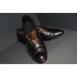 A pair of antique black and brown leather boots having buttons to sides and stack heel, around a