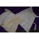 Three antique items of baby clothing including one long gown with cut work and embroidered hem,