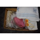 A box full of vintage and antique table line and bed linen, including crotchet edged pillow cases