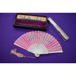 A pink gauze fan in case,having floral embroidery and tassel to carved handle, also included is