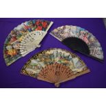 Three colourful paper fans having wooden ribs depicting Spanish scenes and similar, around mid