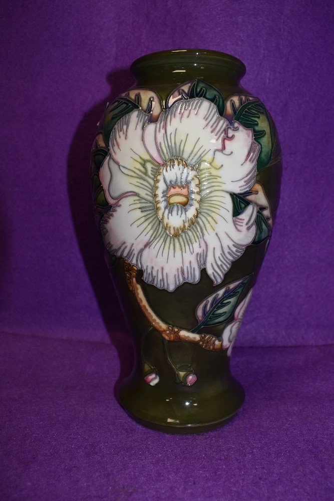 A Moorcroft baluster shaped vase having floral design on dark green ground.