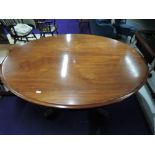 A Victorian mahogany fold over dining table of oval form on pedestal base, with quadruple scroll