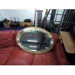 A large Arts and Crafts style brass oval wall mirror, width approx. 100cm