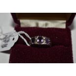 A lady's dress ring having three amethysts in a gallery mount on an HM silver loop, size O