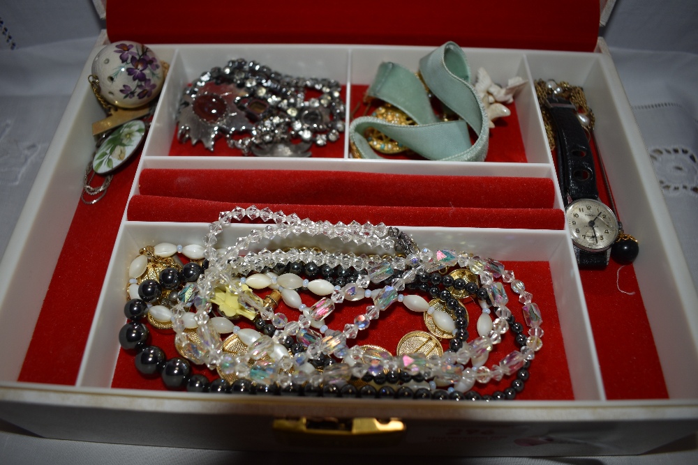 A jewellery box containing a selection of costume jewellery including Ensign watch, brooches,strings