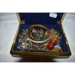 A small travel jewellery case containing a selection of costume jewellery including bangles,