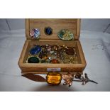 A small wooden box containing a selection of costume brooches and scarf clips including enamelled,