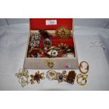 A small vintage jewellery box containing a selection of costume jewellery brooches